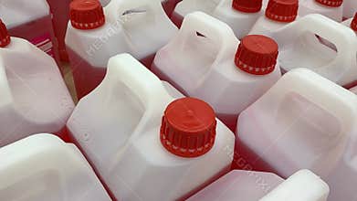 Red capped plastic jugs arranged in rows, ideal for industrial or storage background