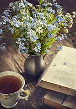 Bouquet of summer blue flowers, cup of tea and vintage books