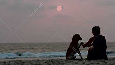 Woman hugs her dog at sunset
