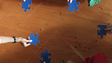 Top down view of business people assemble jigsaw puzzle on table. Convocation.