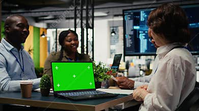 Green screen laptop used by programmers in startup office leveraging AI tech