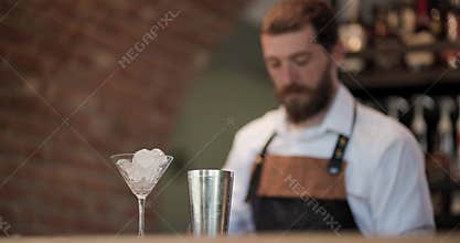 Barman prepares a cocktail with ice at a cozy bar
