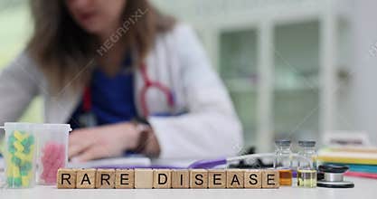 Wooden cubes spell phrase Rare Disease on doctor desk with drugs
