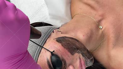 Young woman getting carbon laser facial at beauty clinic. Professional skincare