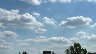 Expansive blue sky filled with fluffy white clouds transitions through a serene landscape, vibrant greenery and structures