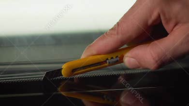 Car wrapping specialists straightening vinyl foil or film to remove ari bubbles cut carbon film. The protective film is removed fr