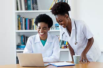 Laughing african american female doctor with young nurse