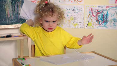 Emotional angry baby tearing painting paper in her room