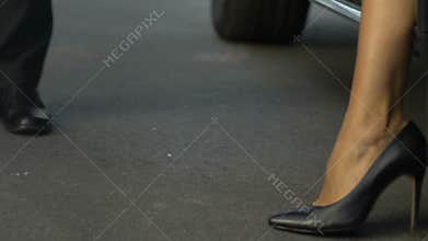 Assistant opening door to female boss, high heeled woman getting out of auto