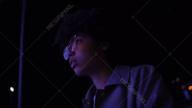 Amazed afro-american girl in eyeglasses watching movie at open-space cinema