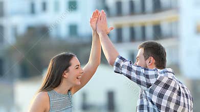 Happy friends giving five in a town