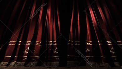 Red theater curtain opens. View of the dark scene.
