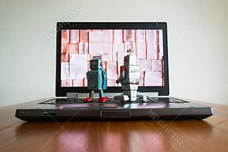 Two robots looking at laptop screen with books, artificial intelligence, big data and deep learning