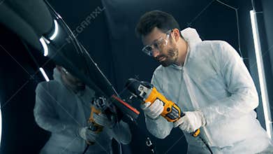 Serviceman is buffing a vehicle with a mechanized device