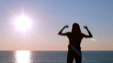 Happy woman celebrating sunrise on the beach