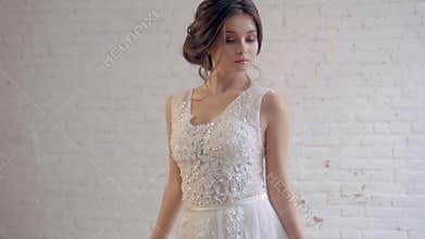 Attractive girl in a light white luxury white wedding dress poses, stands alone in a spacious room, prepares for the