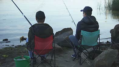 Brothers spending time fishing on lake, family tradition, having fun, laughing