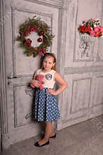 Girl blonde child with a pink teddy bear in hand with a Christmas wreath