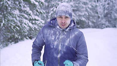 Frozen male athlete runs through the snowy forest, winter activity