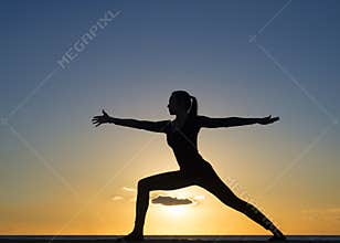 Young healthy woman practicing yoga fitness exercise on the beach at sunset. Healthy lifestyle concept. Copy space text.
