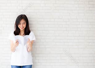 Beautiful of portrait young asian woman happiness relax standing reading book on concrete cement white background at home