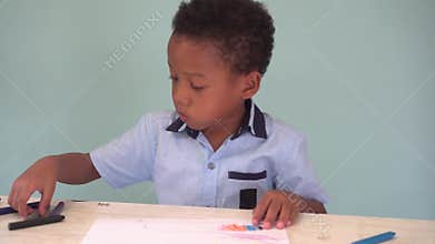African American boy learning how to draw with crayon on table