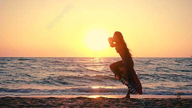 Beautiful girl jumping on the sea coast at sunrise