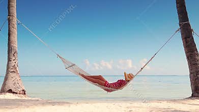 Girl relaxing in a hammock on tropical island beach. Summer vacation