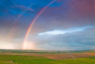 Rainbow with rain clouds and blue sky