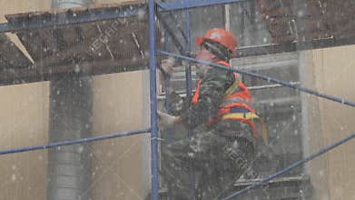 Worker man in uniform and helmet goes up stairs from construction scaffolding