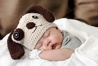 Baby in dog costume sleeping on bed
