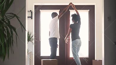 Happy african couple first time home buyers dancing in hallway