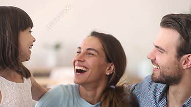Happy parents and child daughter embracing laughing looking at camera