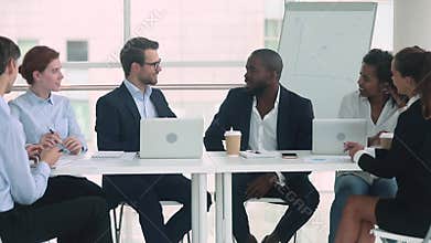 African and caucasian businessmen in suits talking at group negotiations