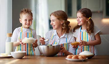 Happy family in kitchen. mother and children preparing dough, bake cookies