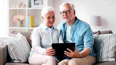 Happy senior couple with tablet computer at home