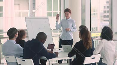 Diverse employees and female coach raise hands at business training