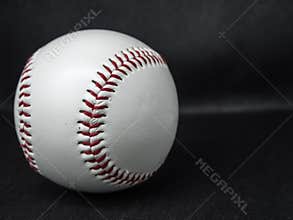 Baseball ball with red threads on a dark background