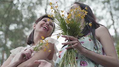 Two beautiful women standing in the forest with amazing wild flowers. Slow motion.