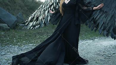 Grim picture, unhappy girl with big black wings and heavy horns alone on head in long flying vintage dark dress with