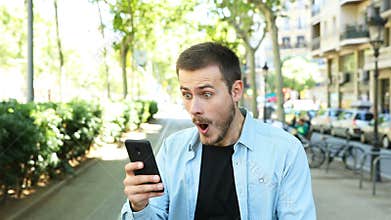 Amazed man using phone looks at camera