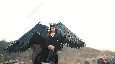 Graceful lady with a menacing look looks into the soul, a girl in a long black dress with lace sleeves lifts the hem of