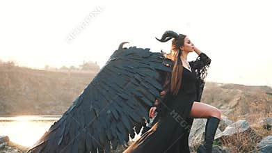 Gorgeous lady with dark soul, queen of night watching sunrise, girl in long light black dress with black feather wings