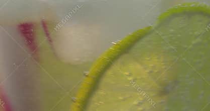 A refreshing drink soda tonic being stir in a glass with ice, and lime.