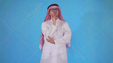 Thoughtful Arab man stands on a blue background