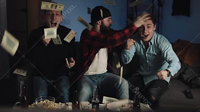 Sports betting. Three friends celebrating success for their favorite football team at home. Dollar bills falling down