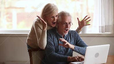 Excited senior couple winners using laptop overjoyed by online win