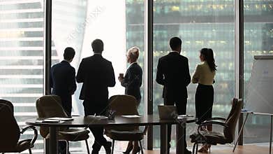Diverse employees group stand separately talking at work, rear view