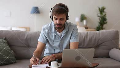 Happy man in headset speaking by webcam looking at laptop