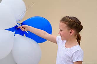 Happy little girl with blue and white balloons.
